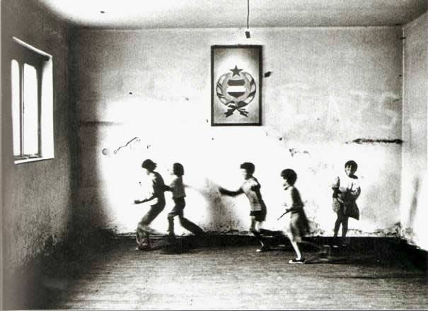 An empty room of a rundown village school with playing children, Tólápa, Hungary 1982